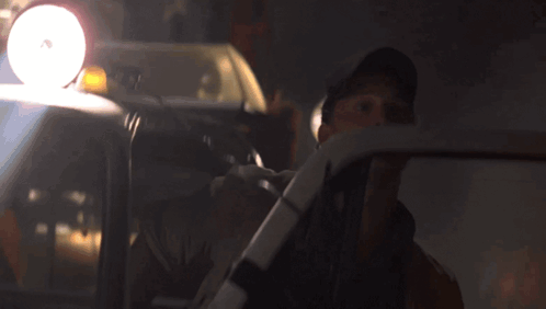 a man in a hat is driving a car with a light on the top of it