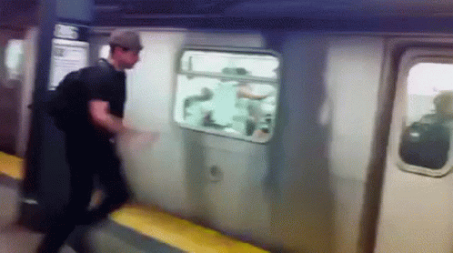 A Man In A Hat Is Getting Off A Subway Car GIF