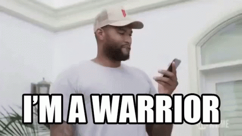 a man in a hat is holding a cell phone and says `` i 'm a warrior '' .