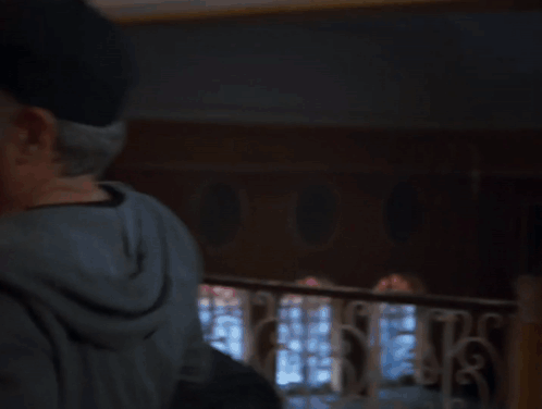 A Man In A Hat Is Hugging A Woman In A Room GIF