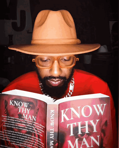 A Man In A Hat Is Reading A Book Titled Know Thy Man GIF