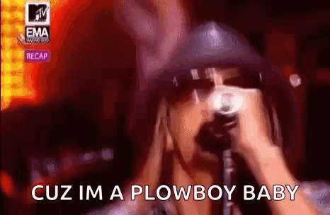 A Man In A Hat Is Singing Into A Microphone . GIF