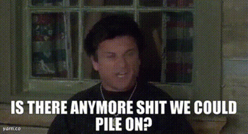 A Man In A Hat Is Sitting In Front Of A Window With The Words `` Is There Anymore Shit We Could Pile On '' . GIF
