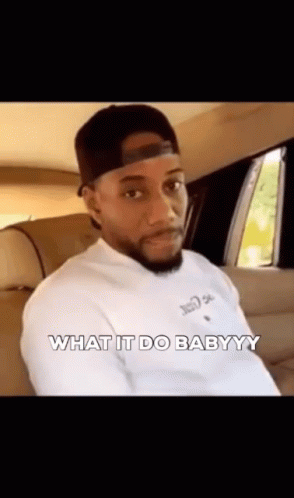 A Man In A Hat Is Sitting In The Back Seat Of A Car And Says `` What It Do Babyyy '' . GIF