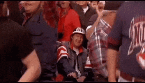 A Man In A Hat Is Sitting In The Stands Watching A Game . GIF