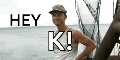 A Man In A Hat Is Standing In Front Of A Body Of Water And Says Hey K! GIF