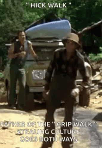 A Man In A Hat Is Standing In Front Of A Car With A Kayak On Top Of It . GIF