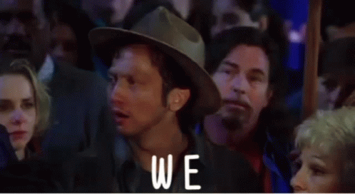A Man In A Hat Is Standing In Front Of A Crowd And The Word Again Is On The Screen GIF