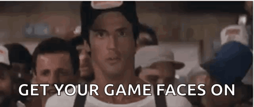 A Man In A Hat Is Standing In Front Of A Crowd Of People With The Words `` Get Your Game Faces On '' . GIF