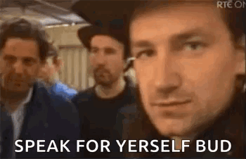 a man in a hat is standing in front of a group of men and says `` speak for yerself bud '' .
