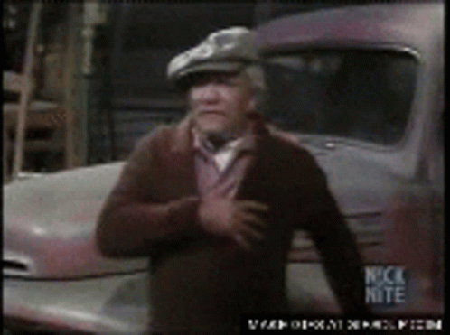 A Man In A Hat Is Standing In Front Of A Truck That Says Nick Nite On It GIF