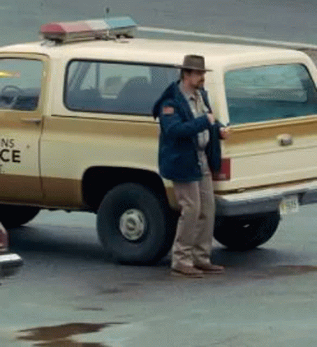 A Man In A Hat Is Standing Next To A Ns Police Truck GIF