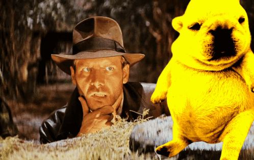 A Man In A Hat Is Standing Next To A Yellow Teddy Bear GIF