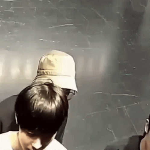 a man in a hat is standing next to another man in a room .