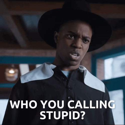 A Man In A Hat Says " Who You Calling Stupid " In Front Of A Window GIF