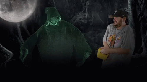 A Man In A Hat Stands In Front Of A Glowing Figure GIF