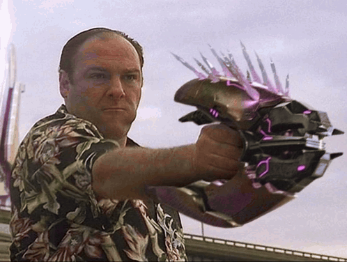 A Man In A Hawaiian Shirt Is Holding A Purple Object With Spikes On It GIF