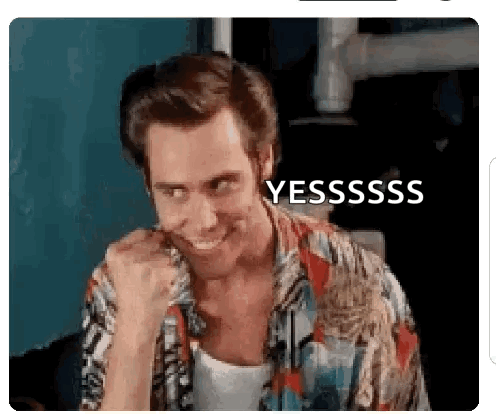 A Man In A Hawaiian Shirt Is Smiling And Making A Funny Face With His Fist In His Mouth . GIF