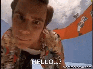 A Man In A Hawaiian Shirt Is Standing In Front Of A Sign That Says Hello . GIF