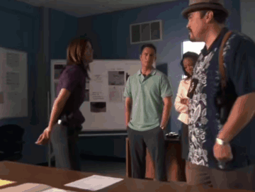 A Man In A Hawaiian Shirt Stands In A Room With Other People GIF