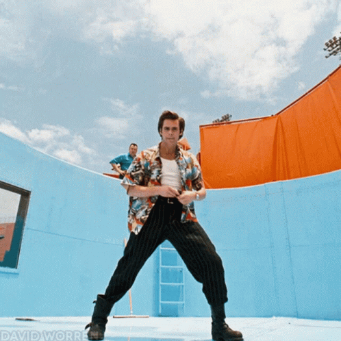 A Man In A Hawaiian Shirt Stands In Front Of A Blue Wall With David Worrell Written On The Bottom Right GIF