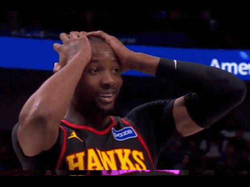 A Man In A Hawks Jersey Is Holding His Head GIF