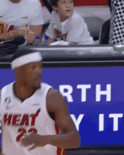 A Man In A Heat Jersey Is Standing In Front Of A Sign That Says Worth It . GIF