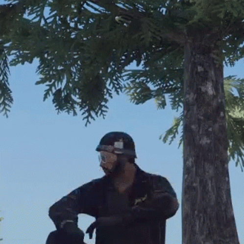A Man In A Helmet And Goggles Is Standing In Front Of A Tree . GIF