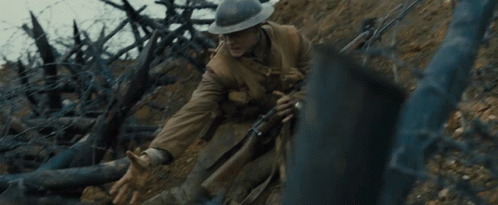 A Man In A Helmet Holds A Rifle In A Trench GIF