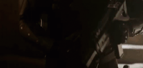 A Man In A Helmet Is Holding A Gun In His Hand . GIF