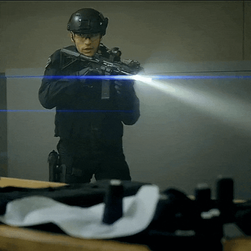 A Man In A Helmet Is Holding A Gun GIF