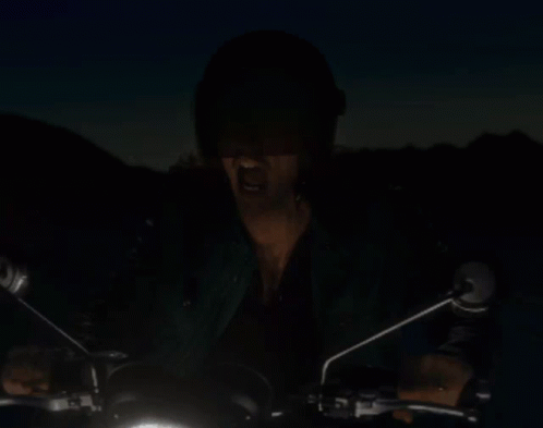 A Man In A Helmet Is Riding A Motorcycle In The Dark GIF