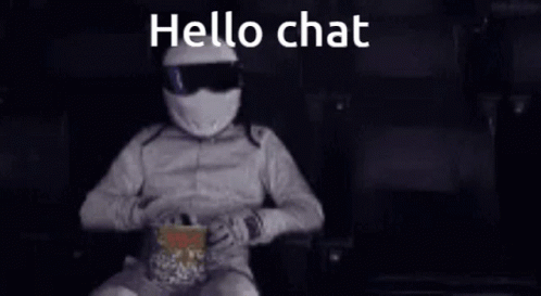 A Man In A Helmet Is Sitting In A Chair Eating Popcorn And Talking On A Cell Phone . GIF