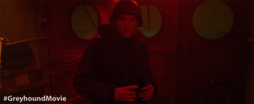 a man in a helmet is standing in a dark room with the hashtag #greyhoundmovie below him
