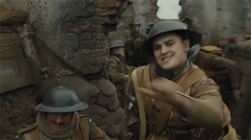 A Man In A Helmet Looks At His Watch In A Trench GIF