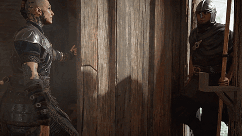 Man In Helmet Standing Next To Man In Black GIF