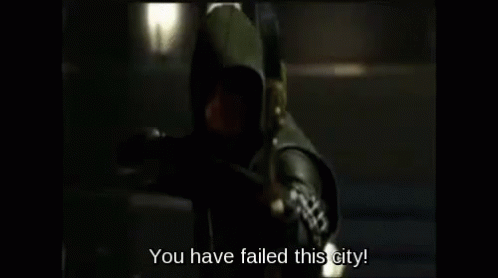 A Man In A Hooded Costume Is Holding A Bow And Arrow And Says `` You Have Failed This City '' . GIF