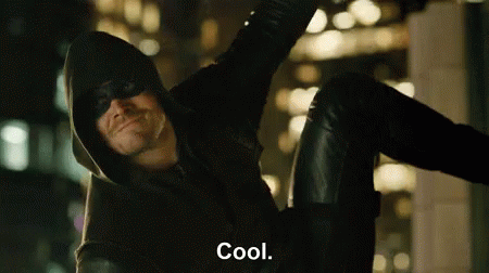 A Man In A Hooded Jacket And Mask Is Sitting On A Wall And Says Cool . GIF