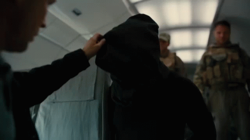 A Man In A Hooded Jacket Is Being Touched By Another Man In A Suit GIF