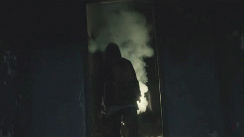 A Man In A Hooded Jacket Is Holding A Light GIF