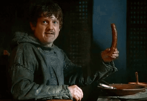 A Man In A Hooded Jacket Is Holding A Sausage In His Hand GIF