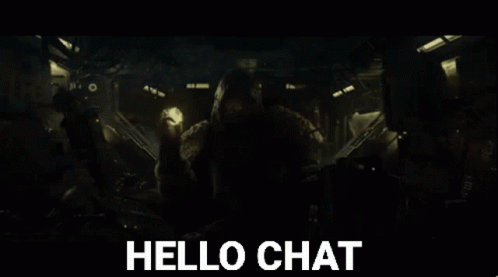 A Man In A Hooded Jacket Is Holding A Torch And Says Hello Chat In The Background GIF