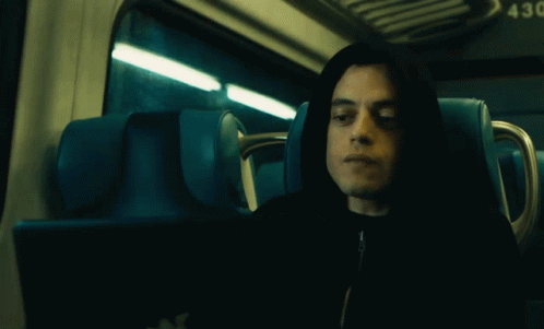 A Man In A Hooded Jacket Is Sitting In A Blue Seat With The Number 43 On The Back GIF