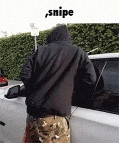 A Man In A Hooded Jacket Is Standing Next To A White Car . GIF