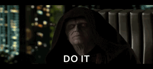 A Man In A Hooded Robe Is Sitting In A Chair With The Words `` Do It '' Written On The Screen . GIF