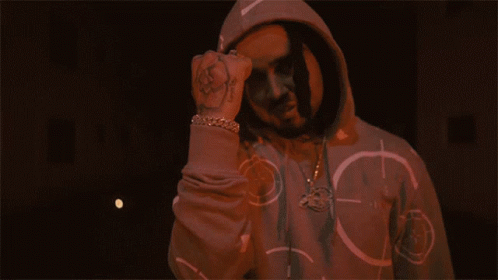 A Man In A Hoodie Is Giving The Middle Finger In Front Of A Fire GIF