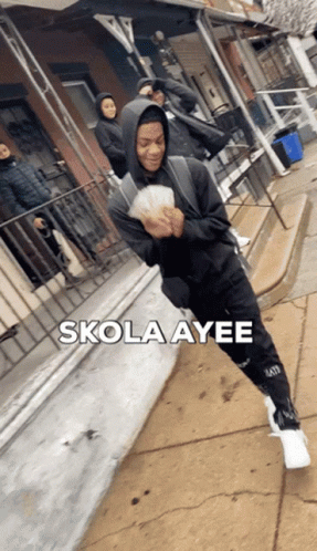 A Man In A Hoodie Is Holding A Bunch Of Money And The Words Skola Ayee Are Above Him GIF