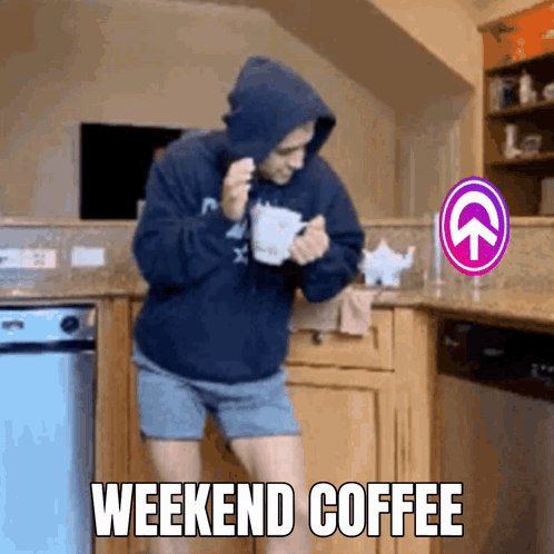 A Man In A Hoodie Is Holding A Cup Of Coffee In A Kitchen With The Words Weekend Coffee Above Him GIF