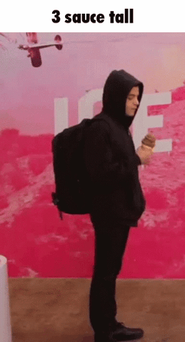 A Man In A Hoodie Is Holding An Ice Cream Cone In Front Of A Pink Wall With The Words 3 Sauce Tall Above Him GIF