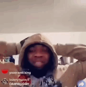 A Man In A Hoodie Is Standing In A Room With His Arms Outstretched And Looking At The Camera . GIF